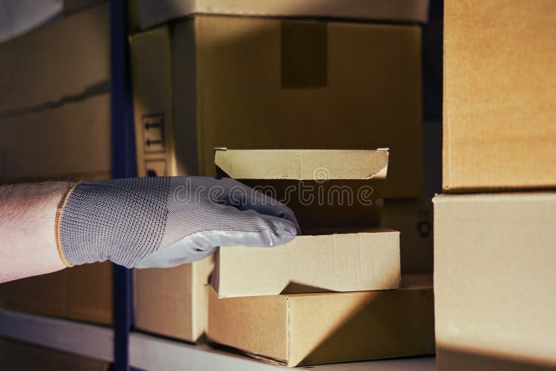 A Man in Gloves Steals Goods from a Box in a Warehouse. Problems with