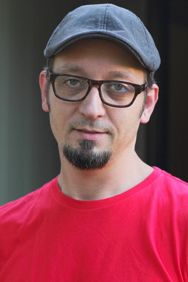 Man with goatee, flat cap and glasses