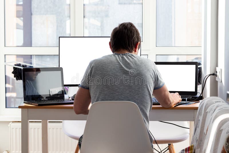 Man working at home using laptop near the big window. Remote work, online  job, work from home. Stock Photo