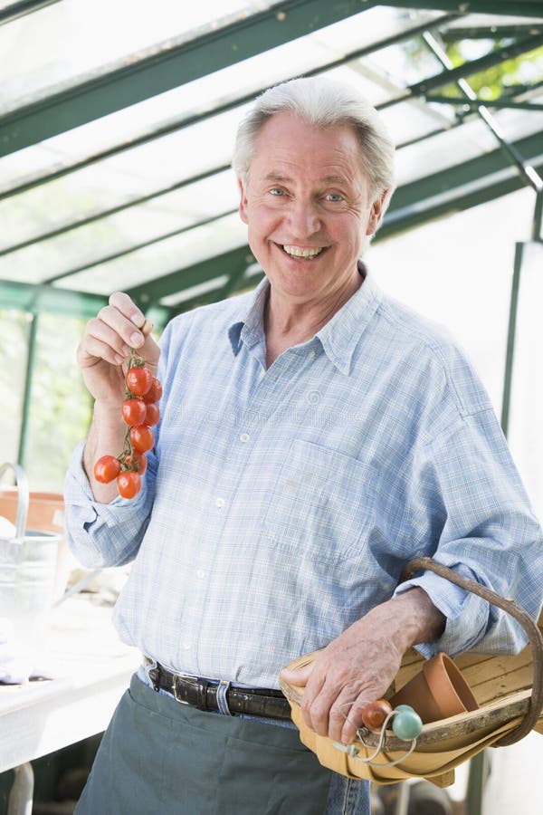 Man in greenhouse holding cherry tomatoes smiling
