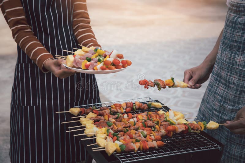 A man grilling pork and barbecue in dinner party. Food, people and family time concept