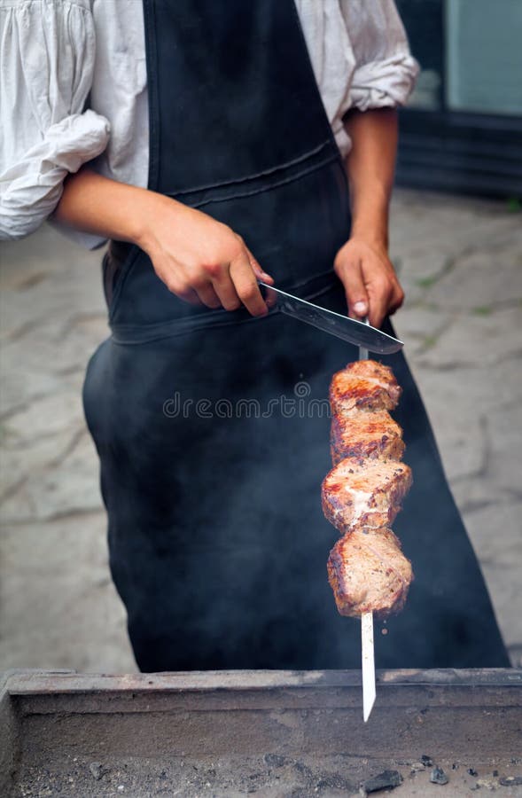 Man grilling traditional party picnic marinated pork beef and lamb on coal ember