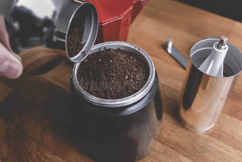 A Man is Grinding Coffee Beans in a Manual Coffee Grinder for an