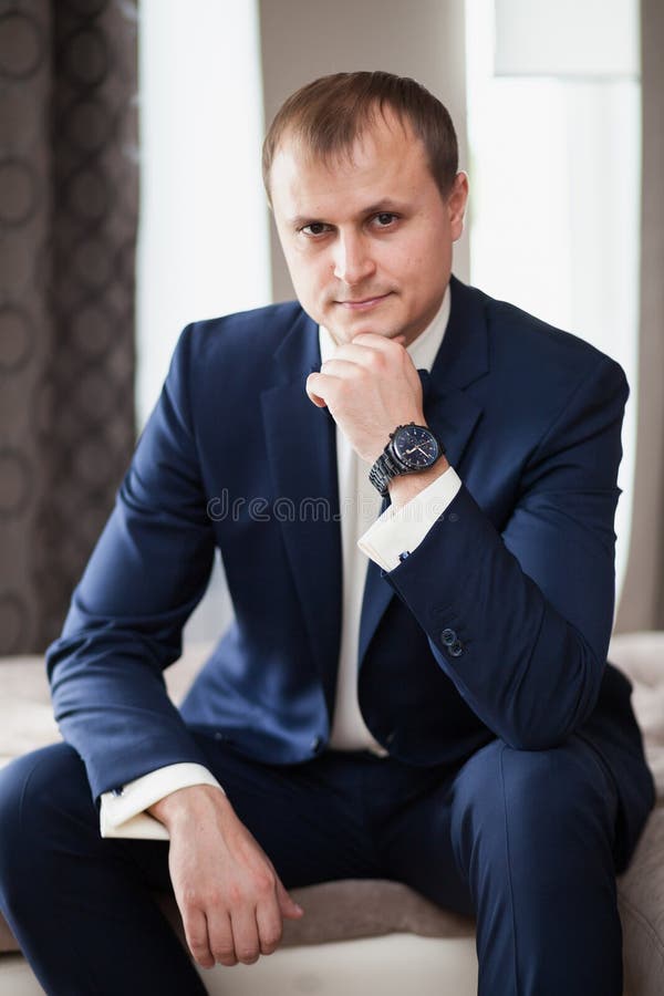 Man the groom in suit sitting on sofa