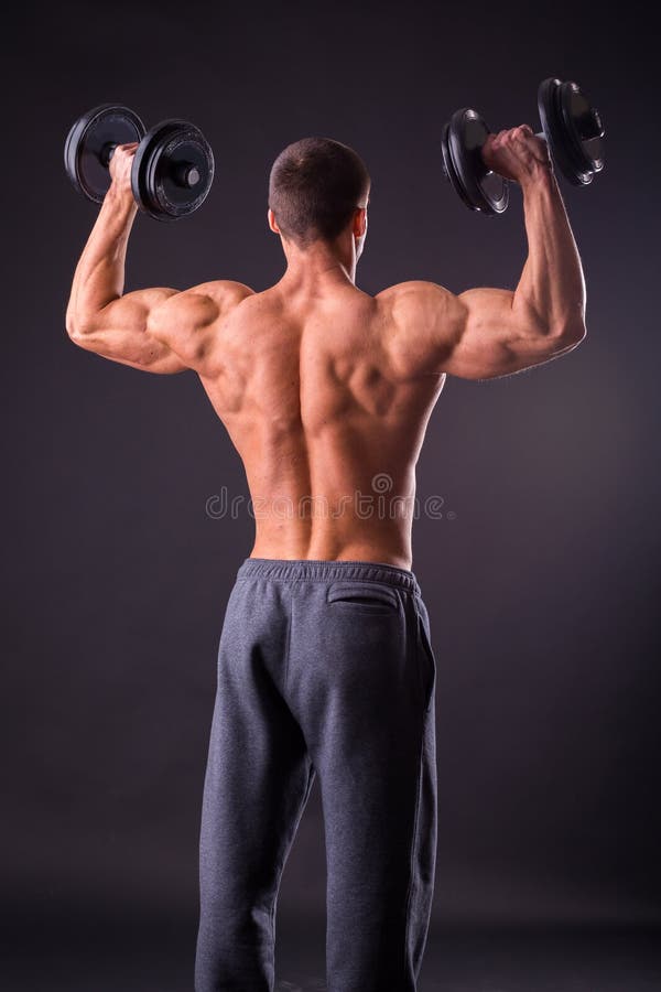 Man at the gym. Man makes exercises dumbbells. Sport, power, dumbbells, tension, exercise - the concept of a healthy lifestyle. Article about fitness and sports.