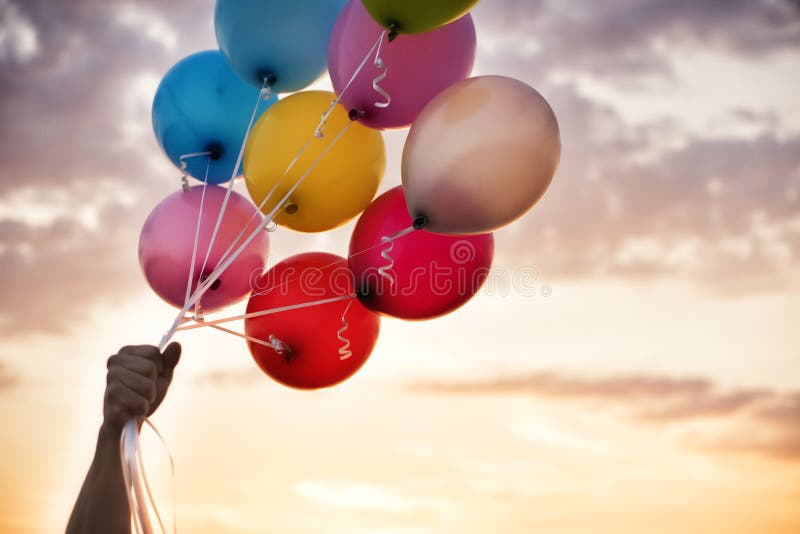 Man Hand Holding Colorful Balloons And A Beautiful Sunset. Birthday Party Balloons royalty free stock image Man Hand Holding Colorful Balloons And A Beautiful Sunset. Birthday Party Balloons royalty free stock image