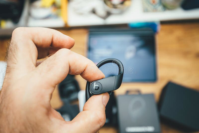 Man hand holding Powerbeats Pro headphone with logotype insignia stock image Man hand holding Powerbeats Pro headphone with logotype insignia stock image