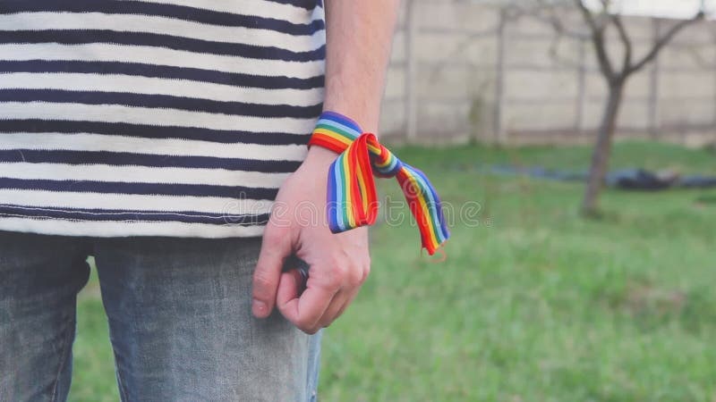 Man hand with LGBT rainbow ribbon tied to the wrists