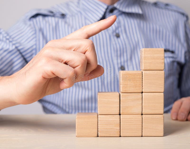 Man hand pointing to career ladder top, pinnacle. Stairs from wooden blocks. Professional development, growth, promotion stock photos