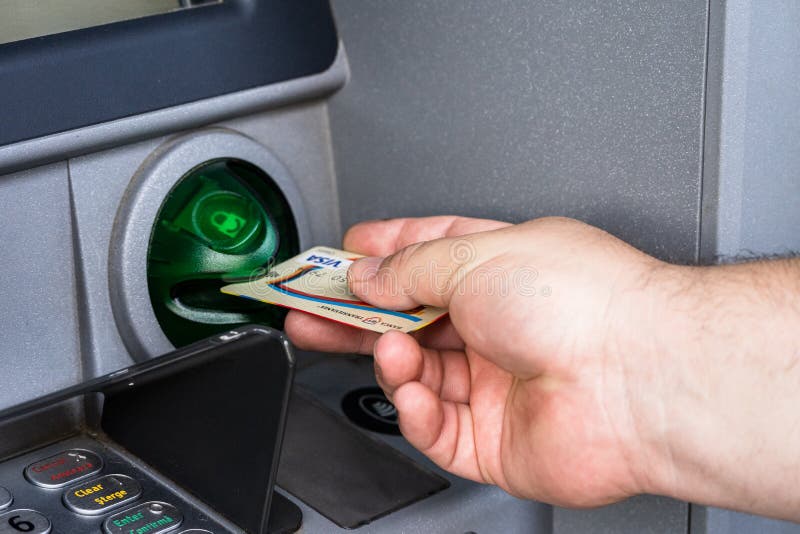 Man hand using VISA credit card at Banca Transilvania ATM. Depositor withdraws money from ATM cash money machine in Bucharest
