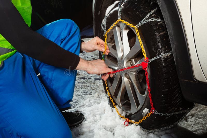 Man hands close-up putting chains on the car wheel
