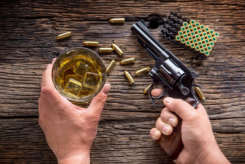 Man Hands Holding Gun and Alcohol Glass on the Table Stock Image