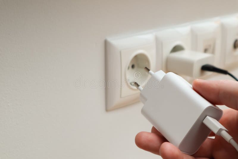 Man Hands Plugging the Charger into an Outlet in the Wall, Closeup. Hand Turns on, Turns Off