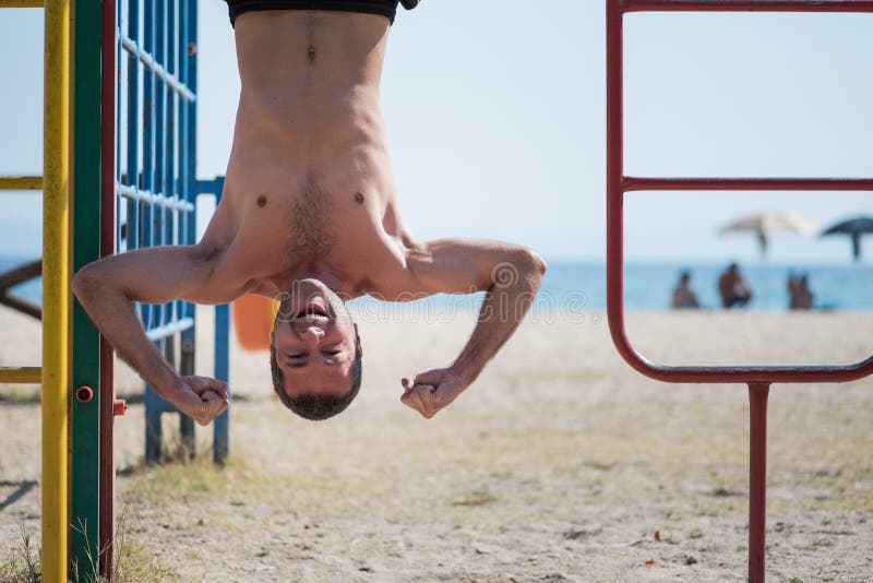 Man hanging upside down at kids playground.