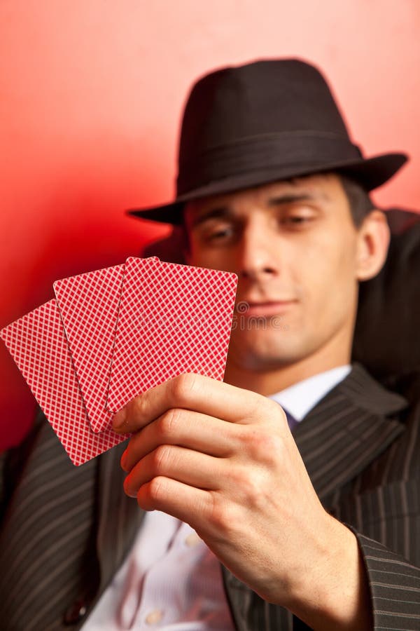 Man with hat playing poker. Focus on cards