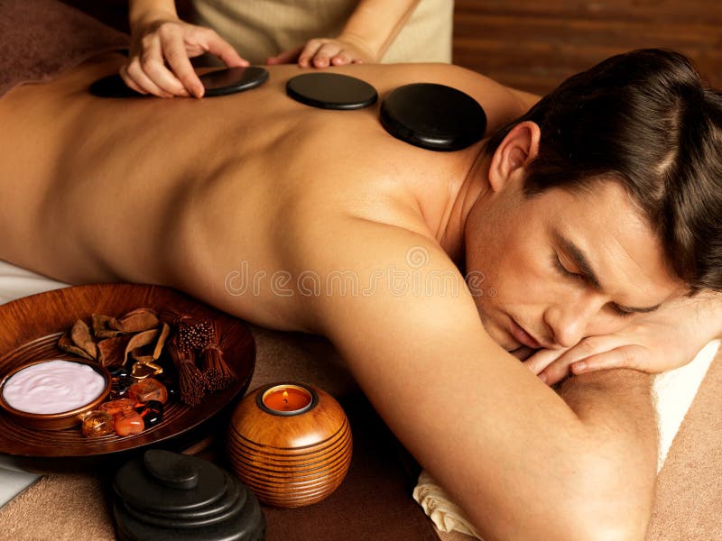 Man having stone massage in spa salon stock photos Man having stone massage in spa salon stock photos