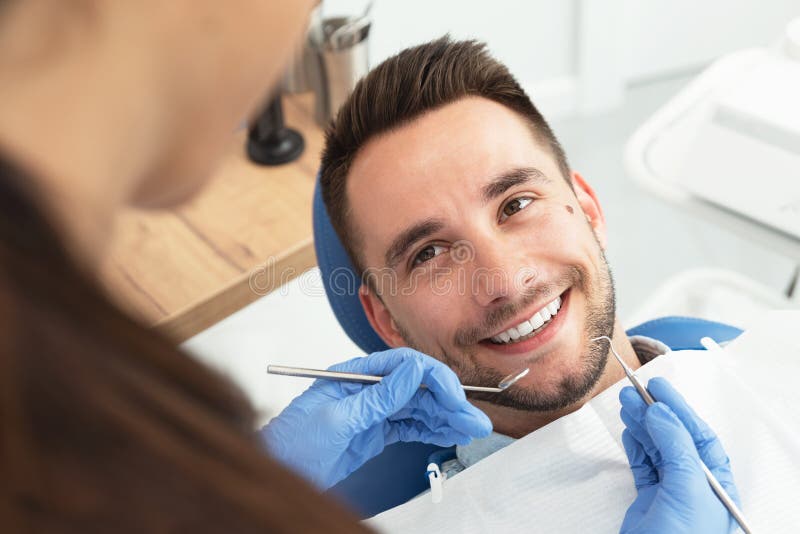 Man having a visit at the dentist`s. Handsome patient sitting on chair at dentist office in dental clinic