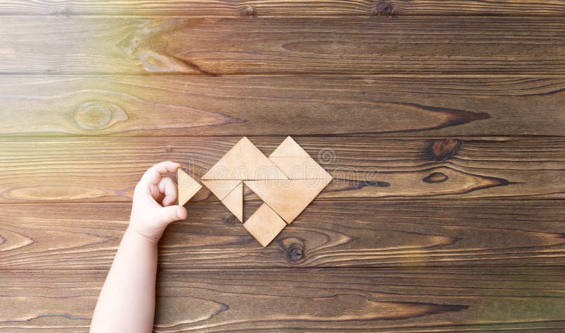 Man held piece of tangram puzzle to fulfill the heart shape on wooden table Concept of love