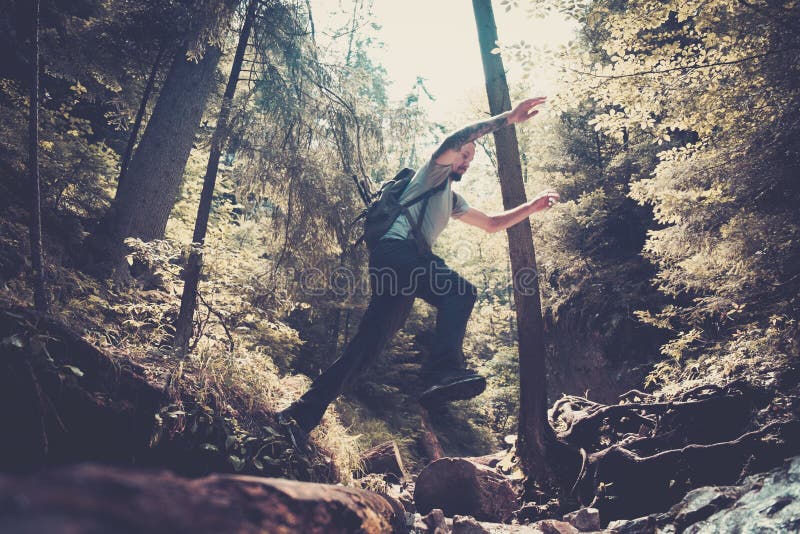 Man hiker jumping across stream