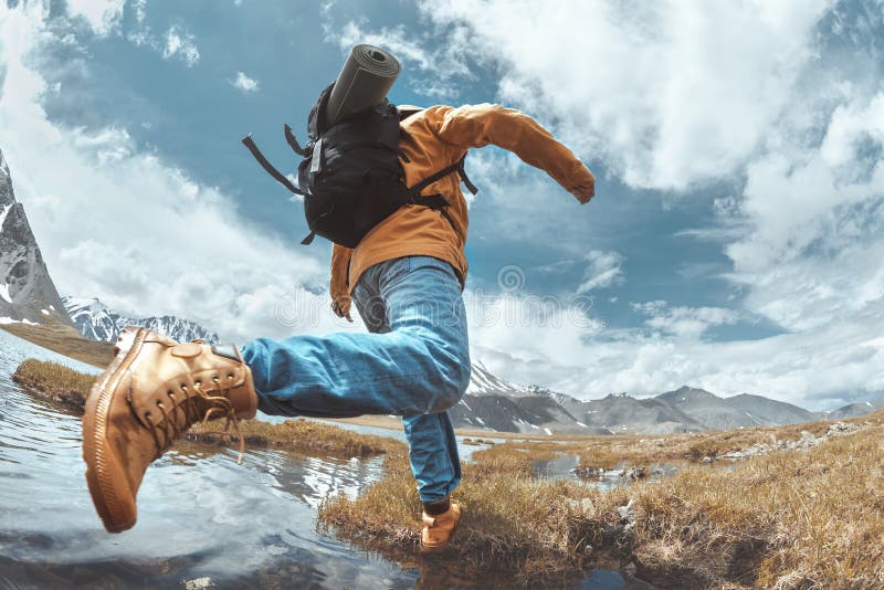 Man hiker jumps across water in mountain area stock image Man hiker jumps across water in mountain area stock image