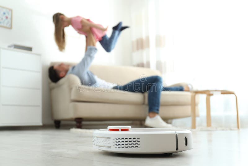 Man and his daughter having fun while robotic vacuum cleaner doing its work