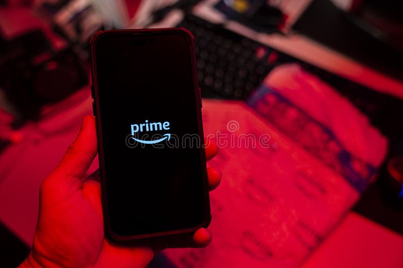 Man holding an Apple iPhone 14 Pro Max smartphone with Amazon Prime Video app on the screen Office environment. royalty free stock photography