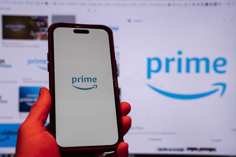 Man holding an Apple iPhone 14 Pro Max smartphone with Amazon Prime Video app on the screen Office environment. royalty free stock photography