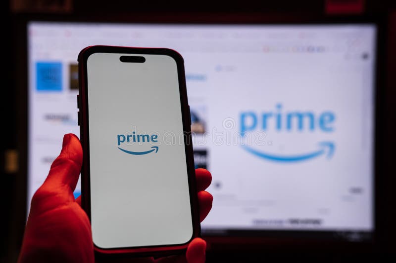 Man holding an Apple iPhone 14 Pro Max smartphone with Amazon Prime Video app on the screen Office environment. royalty free stock image