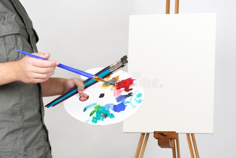 Man holding brushes and palette, canvas on easel