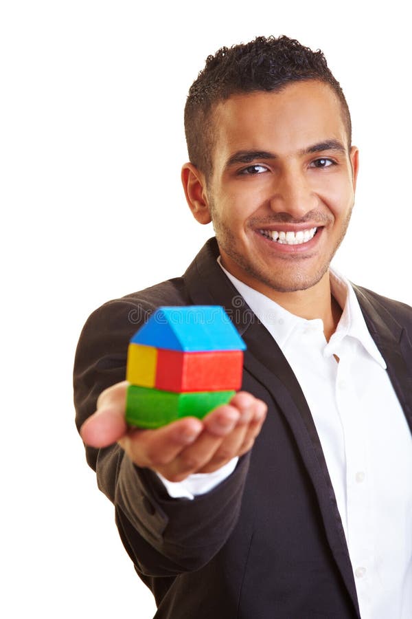 Young manager holding a house made of building bricks. Young manager holding a house made of building bricks