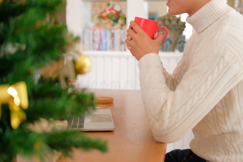 Man holding coffee cup & using computer at home during christmas royalty free stock photography