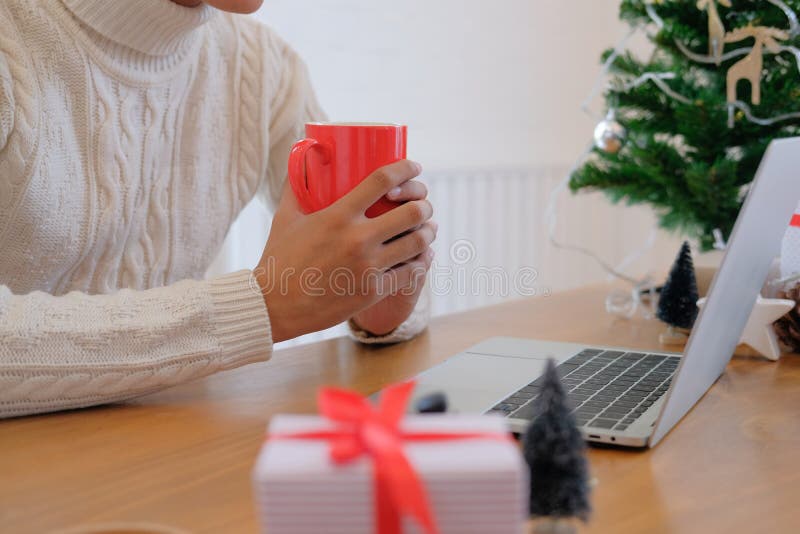 Man holding coffee cup & using computer at home during christmas stock photos