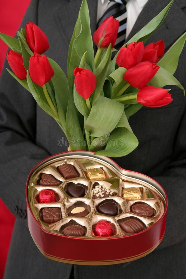 Man Holding Heart Shaped Box of Candy and Red Tulips. Male hand holding businessman stock images, royalty-free photos and pictures