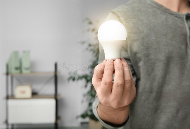 Man Holding Lamp Bulb on Blurred Background, Closeup Stock Image