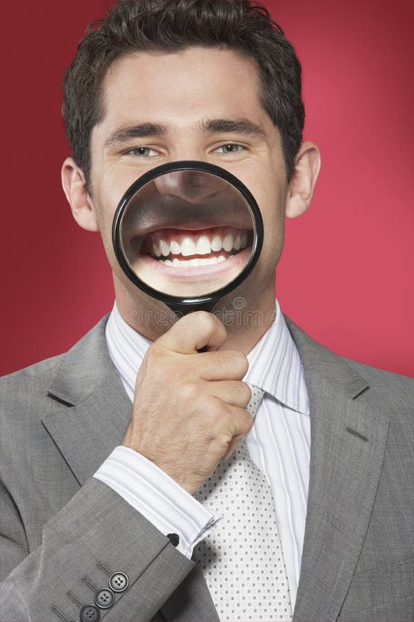 Man Holding Magnifying Glass To Smiling Mouth stock photos Man Holding Magnifying Glass To Smiling Mouth stock photos