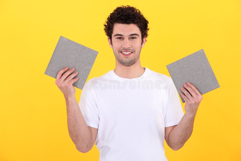 Man holding up tiles in each hand