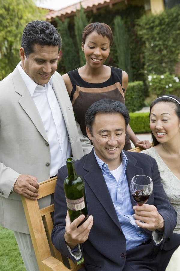 Man Holding Wine Bottle And Glass With Friends In Park royalty free stock photos Man Holding Wine Bottle And Glass With Friends In Park royalty free stock photos