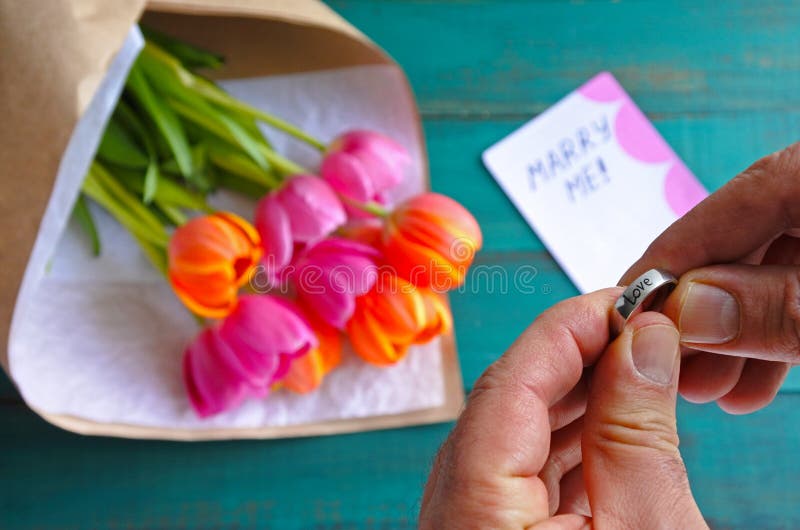 Man holds an engagement ring over a Marry me message note stock photography Man holds an engagement ring over a Marry me message note stock photography