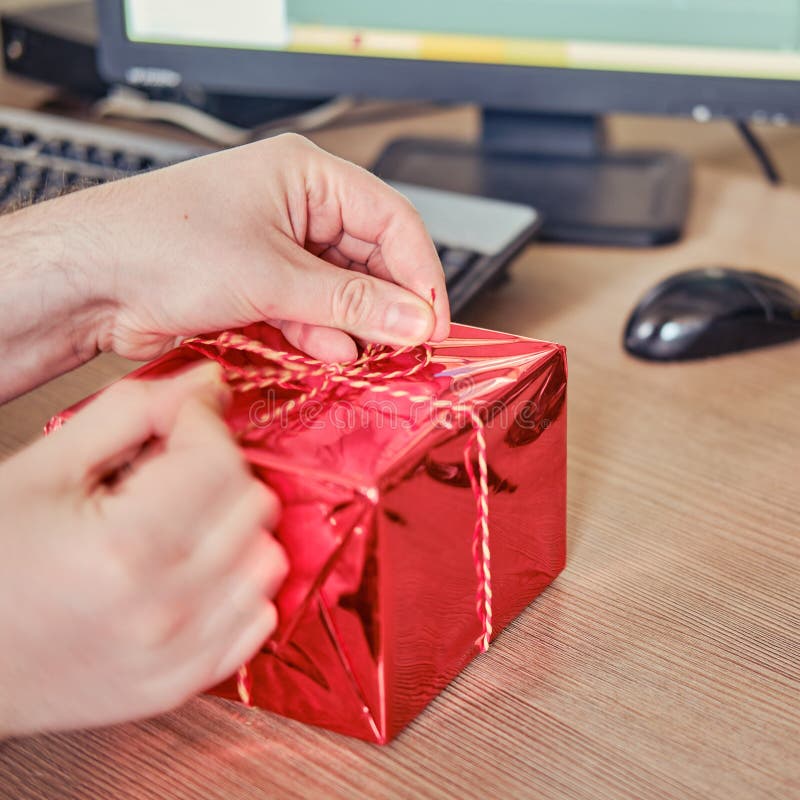 A Man Holds a Gift on His Office Desk at Christmas and New Year