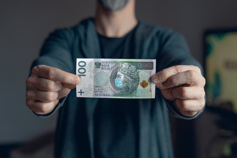 Man holds in hands 100 zlotych banknote with a face mask against Corona virus infection royalty free stock images.