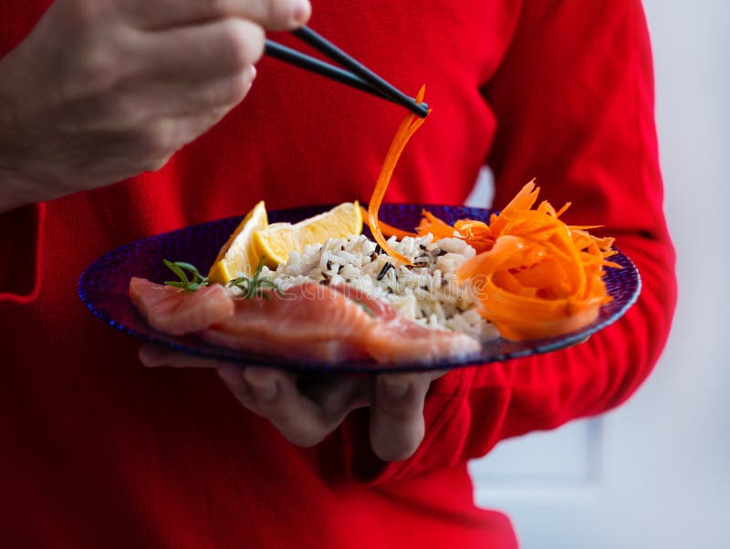 Man Holds Healthy Food Balanced Meal with Salmon Fish Wild Rice Carrots