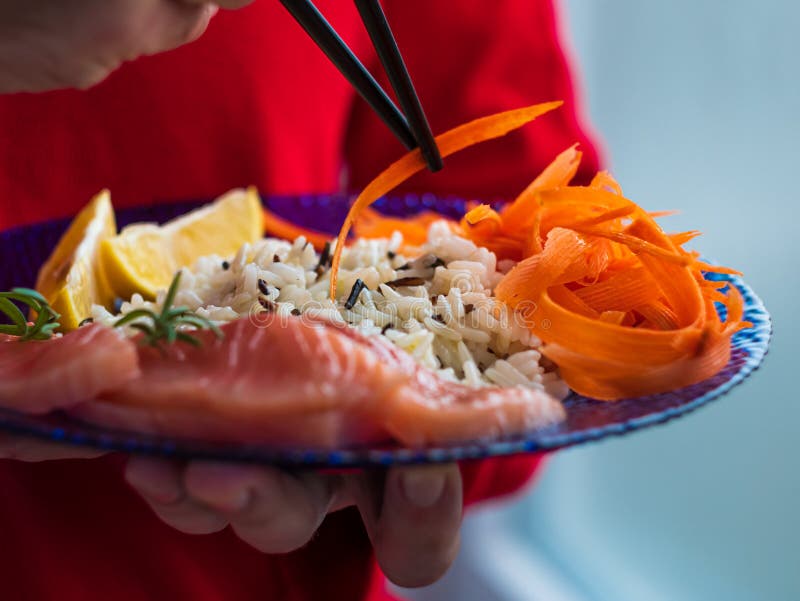 Man Holds Healthy Food Balanced Meal with Salmon Fish Wild Rice Carrots