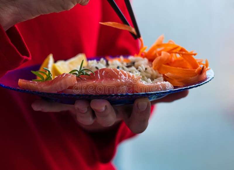 Man Holds Healthy Food Balanced Meal with Salmon Fish Wild Rice Carrots