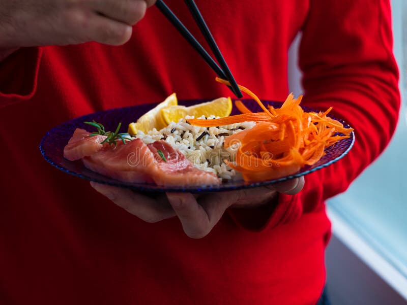Man Holds Healthy Food Balanced Meal with Salmon Fish Wild Rice Carrots
