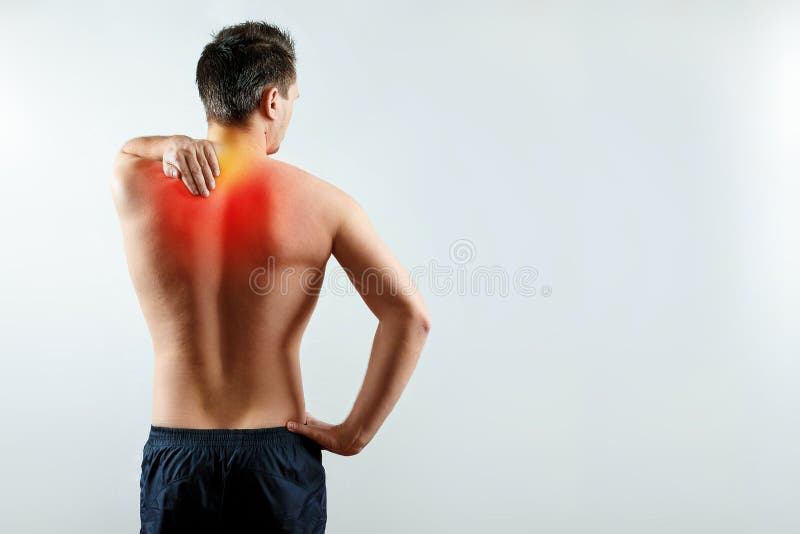 A man holds his hands for a damaged shoulder, a pain in his shoulder highlighted in red. Light background. The concept of medicine.