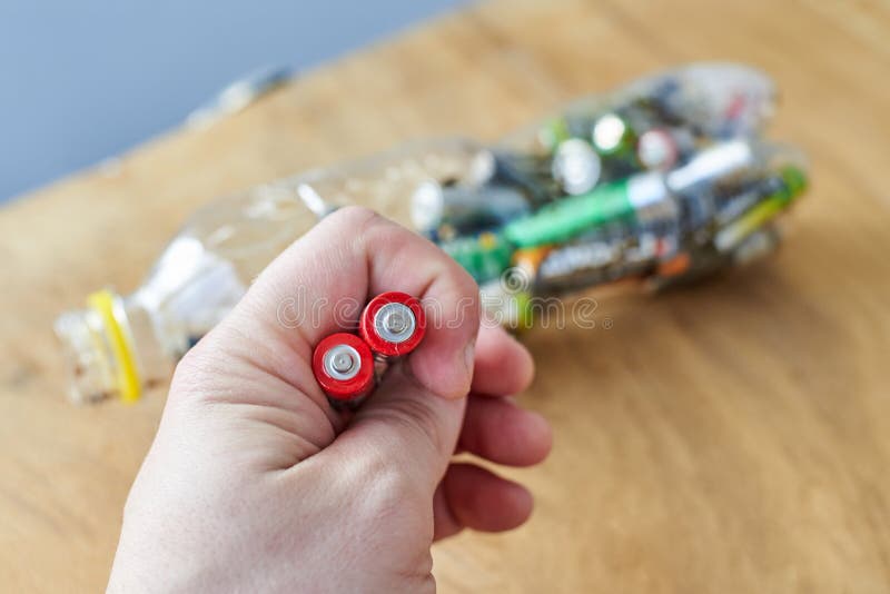 A man holds used batteries to throw in a plastic bottle, the topic of sorting garbage royalty free stock photo A man holds used batteries to throw in a plastic bottle, the topic of sorting garbage royalty free stock photo
