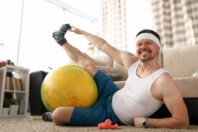 Man at home doing fitness with dumbbells and ball