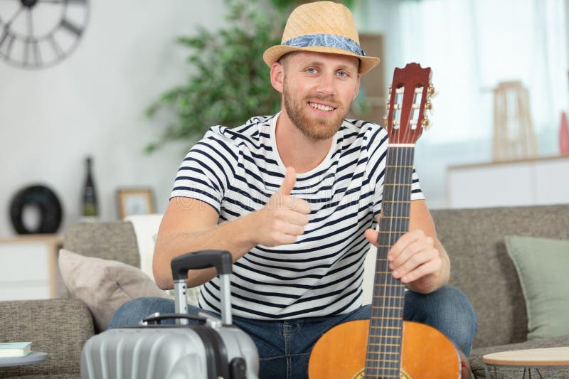 Man at Home about To Travel with Suitcase and Guitar Stock Image