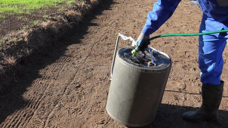 Man with hose filling soil ground hardener roller with water. Static shot