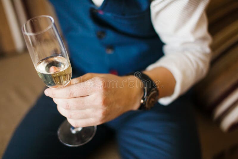 Man hållande exponeringsglas av champagne i hand på soffan arkivbild Man hållande exponeringsglas av champagne i hand på soffan arkivbild